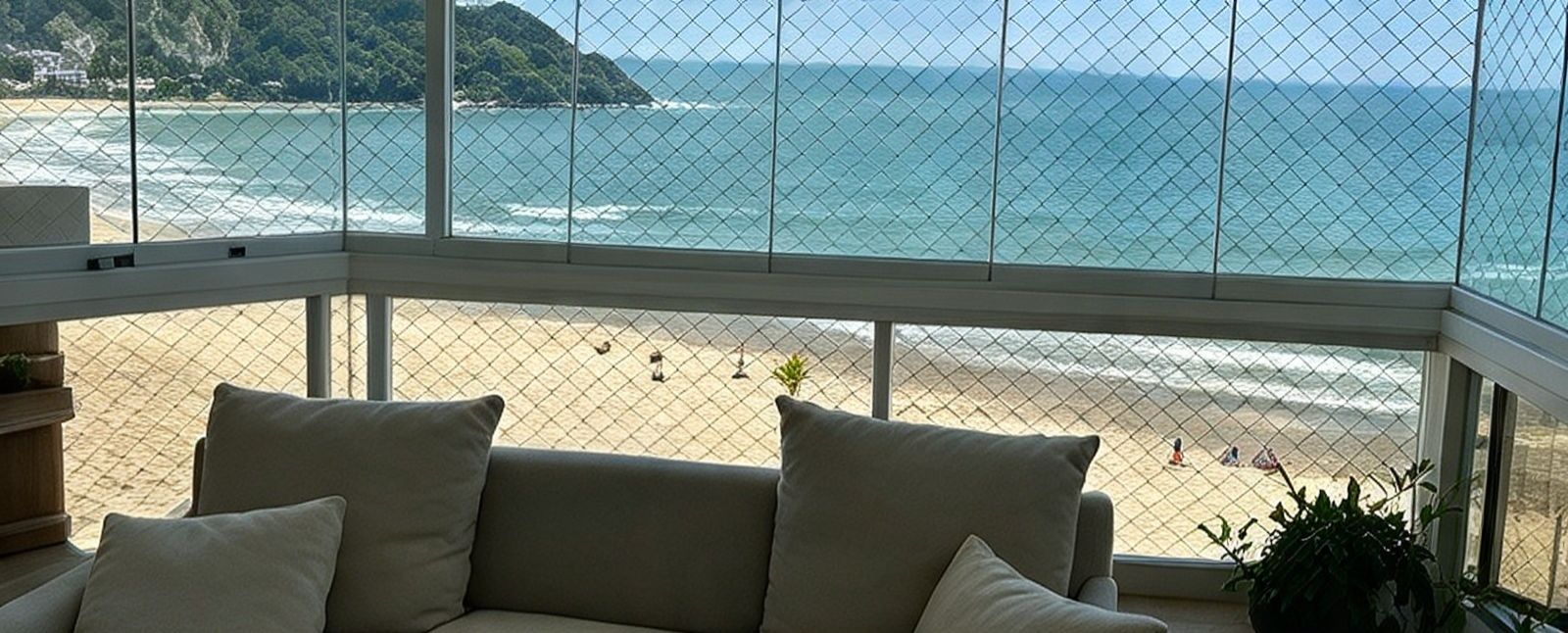 Sacada de canto envidraçada, com rede de proteção e vista para a praia